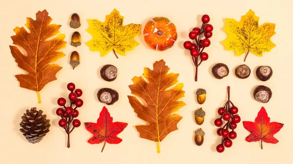 Autumn layout arrangement on beige background. Fall leaves and nuts pattern. Flat lay concept