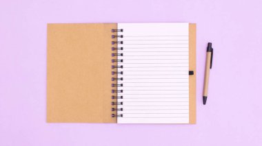 Open notebook with pencil on pastel purple background. Flat lay copy space