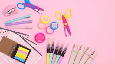 Pastel pink background with Back to school supplies and copy space on right side. Flat lay. Creative concept
