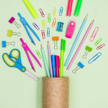 Pencil pen cup with school stationery on pastel green background. Back to school flat lay