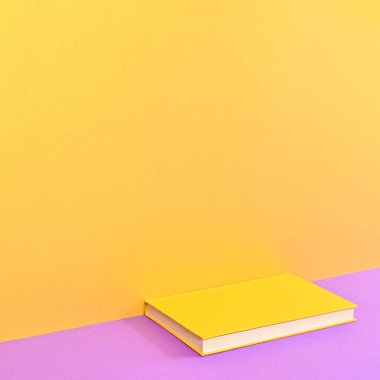 Creative background with copy space and hardcover book on golden purple background. Flat lay minimal concept
