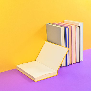 Creative composition of hardcover books with open book copy space on golden purple backgorund. Flat lay