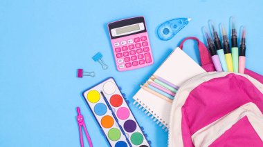 Backpack and school stationery on pastel blue background. Flat lay