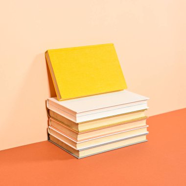 Creative arrangement of vintage books on two shade orange background. Flat lay copy space