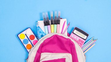 Backpack and school stationery on pastel blue background. Flat lay