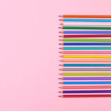 Colorful wooden pencils on pastel pink background. Flat lay copy space