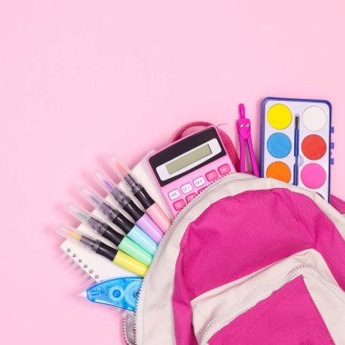 Back to school backpak with school stationery on pastel pinkbackground. Flat lay