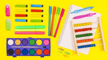 Vibrant yellow background with Back to school stationery arrangement. Flat lay