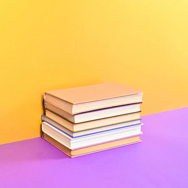 Hardcover vintage books ordered on golden purple background. Flat lay