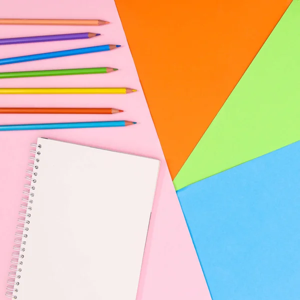 Colorufl background with colorful wooden pencils and open notebook with copy space. Flat lay