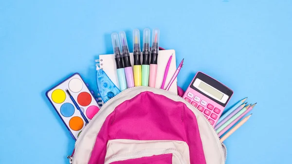 Backpack and school stationery on pastel blue background. Flat lay