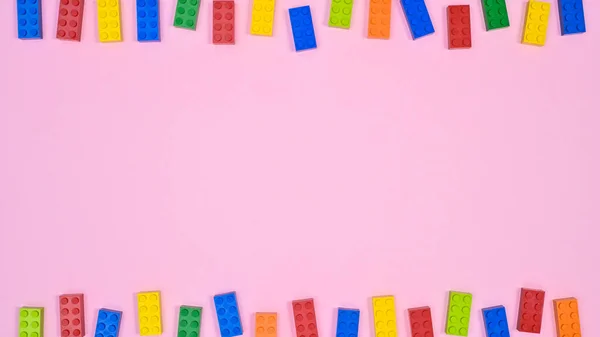 Colorful bricks toys on pastel pink background. Flat lay sopy space