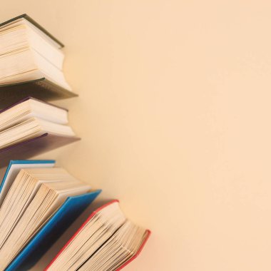 Pastel beige background with copy space and vintage colorful books. Flat lay