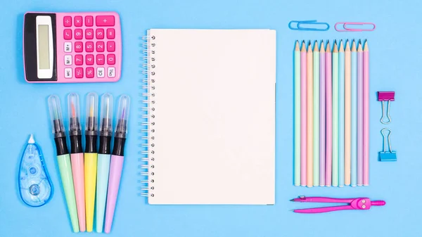 Back to school pastel blue background with school supplies and paper card copy space. Flat lay. Back to school concept