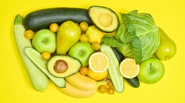Creative layout of green and yellow fruits and vegetables on yellow background. Antioxidant and healthy lifestyle concept. Flat lay