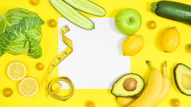Creative copy space on yellow background with green and antioxidant fruits and vegetables. Flat lay diet and healthy concept.
