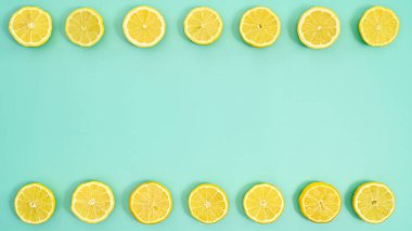 Half sliced lemons on top and bottom of cyan background. Flat lay. Summer copy space concept