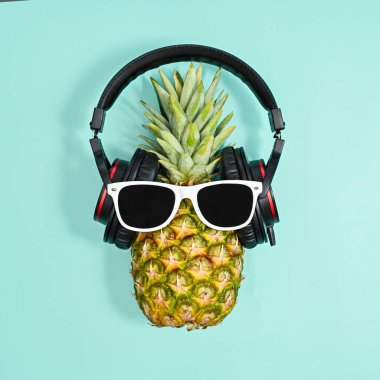Creative pineapple with headphones and sunglasses on pastel cyan baclground. Creative summer disco concept. Flat lay