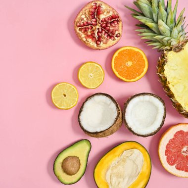 Ripe organic half sliced tropic fruits on pastel pink background. Flat lay. Summer cncept