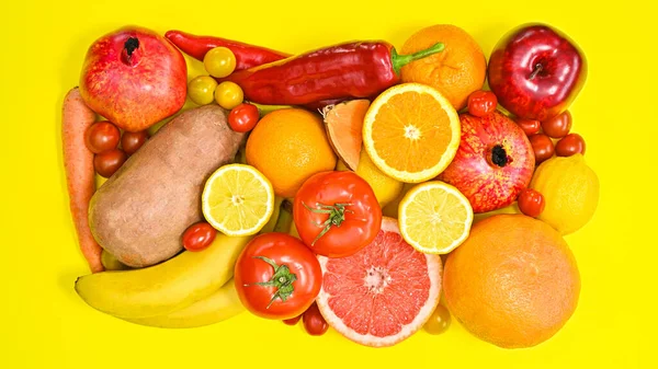 Red fruits and vegetables pile on vibrant yellow background. Creative healthy food concept. Flat lay