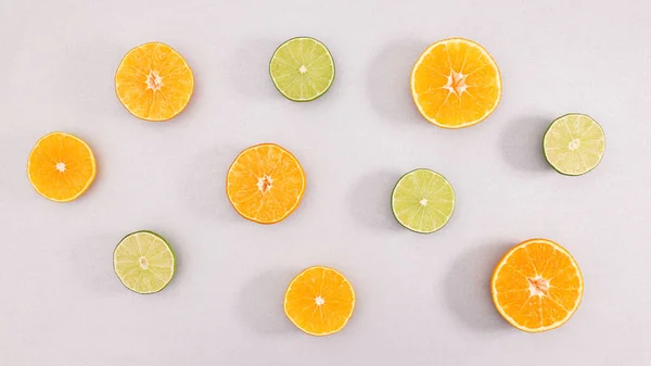 stock image Sliced fresh lemons and limes on grey background. Summer exotic citrus fruits concept