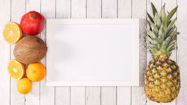 White copy space frame with exotic summer fruits on wooden background. Flat lay