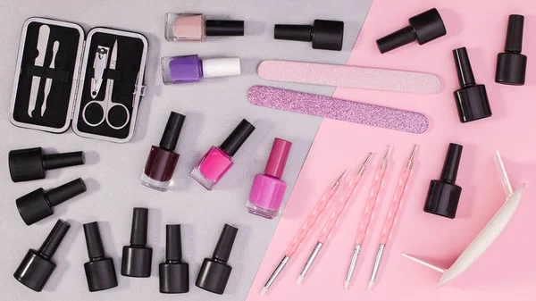 Nail care products and manicure set on pastel pink and grey background. Flat lay