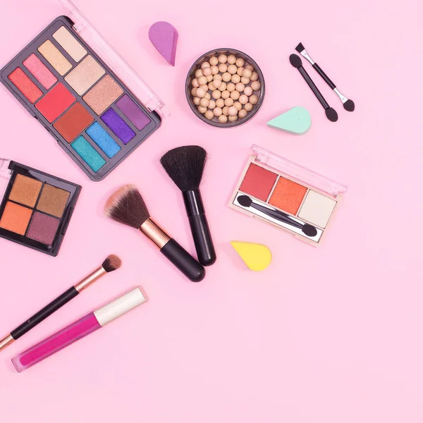 Colorful make up products layout on pastel pink background. Flat lay