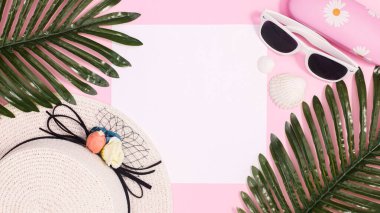 Summer beach background with hat and beach accessories on pastel pink background with copy space. Flat lay