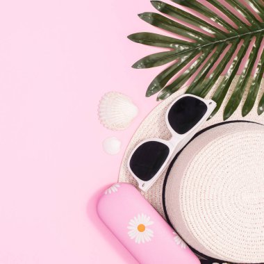 Summer beach background with hat and beach accessories on pastel pink background. Flat lay