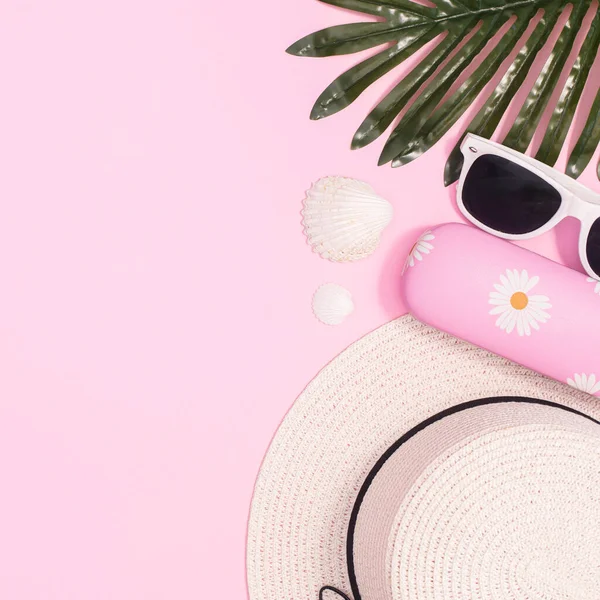 Summer beach background with hat and beach accessories on pastel pink background. Flat lay