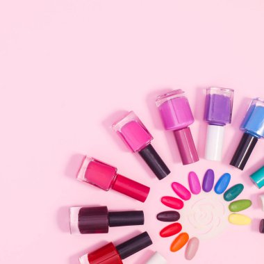 Nail polish bottles on pastel pink background with copy space. Flat lay