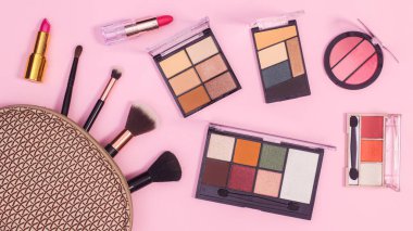 Make up products in cosmetics kit on pastel pink background. Flat lay