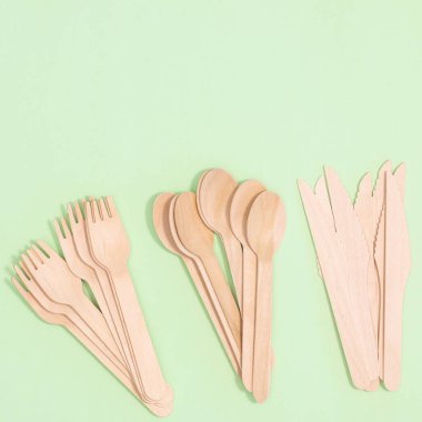 Wooden zero waste forks, knifes and spoons on pastel green background. Flat lay