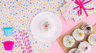 Birthday party cup cakes and accessories on pink background. Flat lay