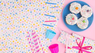 Birthday party cup cakes and accessories on pink background. Flat lay