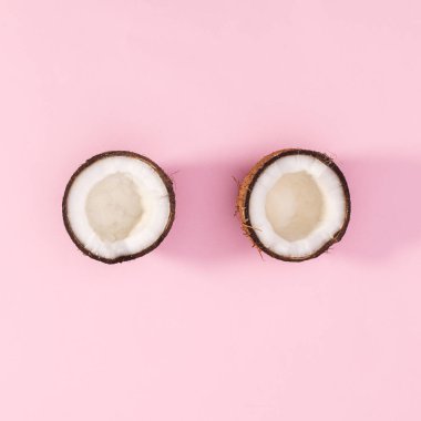 One coconut broken in two peaces on pastel pink background. Flat lay