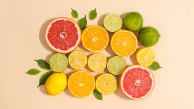 Summer composition of citrus fruits and green leaves on beige background. Flat lay