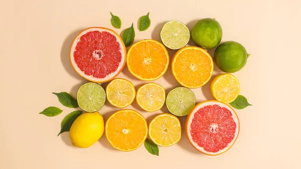 Summer composition of citrus fruits and green leaves on beige background. Flat lay