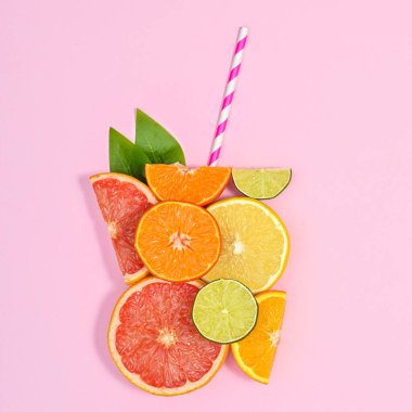 Creative glass of juice made of citrus fruits with straw on pastel pink background. Flat lay