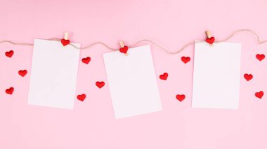Romantic paper with copy space hanged on rope on pastel pink background. Flat lay Valentine's day