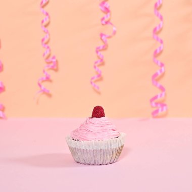 Sweet cup cake with pastel pink cream and raspberry on the top