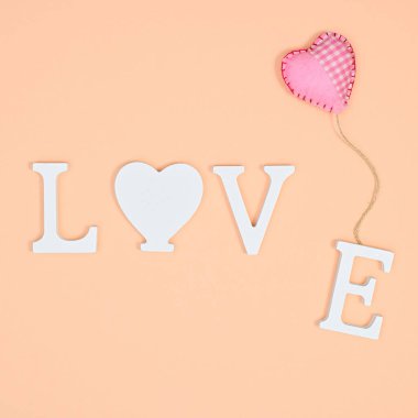 Creative Valentine's day concept with love word and heart baloon on pastel orange background. Flat lay