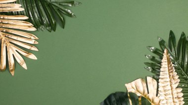 Summer exotic palm leaves on green background. Flat lay copy space