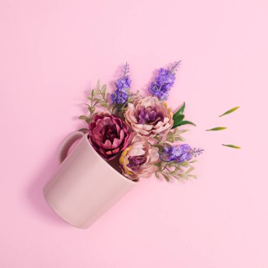 Pastel pink ceramic cup with spring flowers in it. Flat lay creative concept