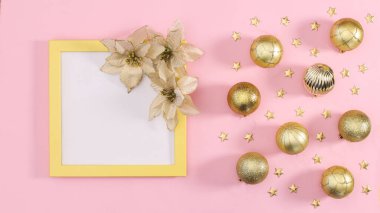 Uzay çerçevesini, Noel tatili için pastel pembe arka planda altın süslerle kopyalayın. Düz yatıyordu