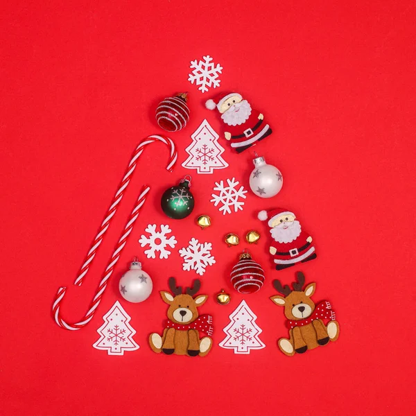 具有创意的圣诞树形状 由各种红色背景的装饰品制成 平躺在床上 — 图库照片