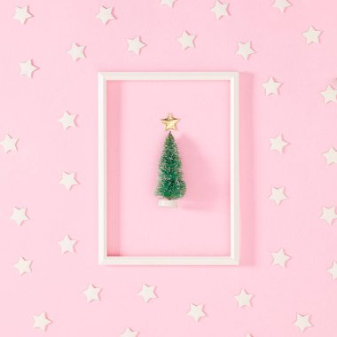 Beyaz çerçeveli küçük Chrimtas ağacı beyaz yıldızlı, pastel pembe arka planda. Düz yatıyordu