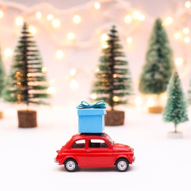 Çatıda mavi hediyeli küçük kırmızı bir araba. Yaratıcı ve şirin noel ağaçları ile Noel arkaplanı