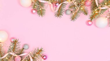 Fotokopi alanı ile pembe arka plan ve ışıklarla süslenmiş gümüş çam dalları ve pembe ve beyaz süslemeler. Düz yatıyordu